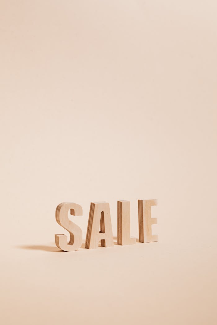 Home Wooden letters spelling SALE on a neutral beige background, perfect for promotions.